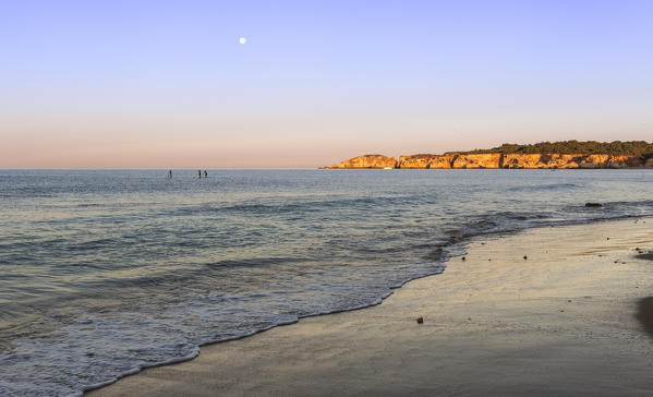 The pink sky at dawn lights up the ocean and cliffs at Praia do Vau Portimao Faro district Algarve Portugal Europe