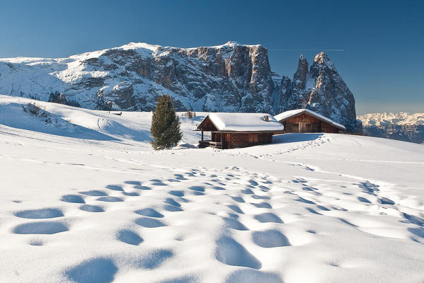 Traditional huts of the Dolomites after a winter snowfall overlook the scenery of the Group Sciliar. Siusi. Western Dolomites. Trentino Alto Adige. Italy. Europe