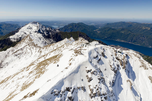 Aerial view of snowy peaks of Grignone with Brioschi Refuge on top and lake in background Lecco Province Lombardy Italy Europe