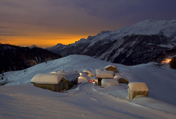 The mountain huts of the Andossi Alp in a full moon night. Chiavenna. Valchiavenna. Vallespluga. Valtellina. Lombardy. Italy. Europe 