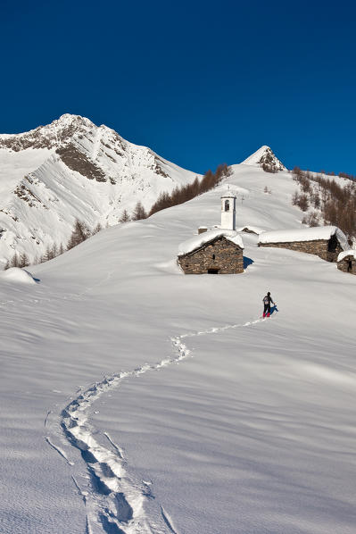 Footsteps in the snow of a hiker with snowshoes trying to reach the Scima Alp. In the background Forcola Peak. Chiavenna. Valchiavenna. Vallespluga. Valtellina. Lombardy. Italy. Europe