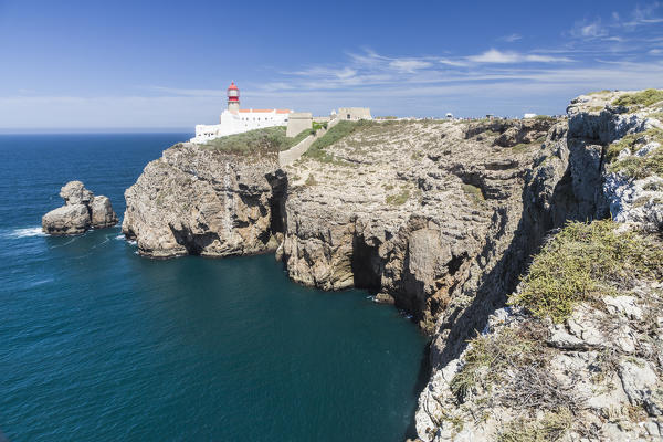 The cliffs and lighthouse overlooks the blue Atlantic ocean at Cabo De San Vicente Sagres Algarve Portugal Europe