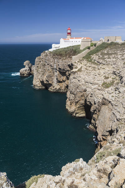The cliffs and lighthouse overlooks the blue Atlantic ocean at Cabo De San Vicente Sagres Algarve Portugal Europe