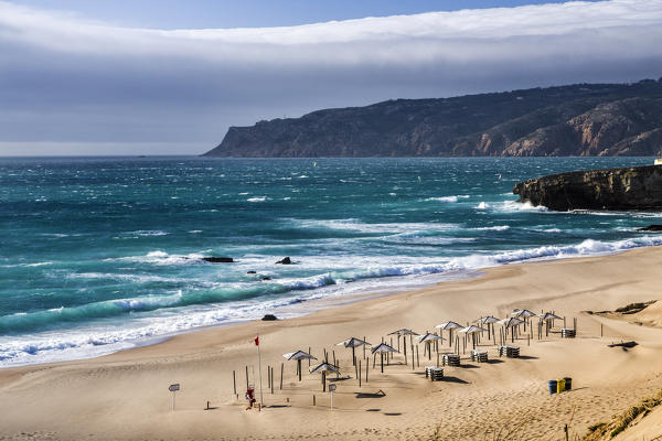 Ocean waves crashing on the sandy beach and bathhouse of Cascais surrounded by cliffs Estoril Coast Lisbon Portugal Europe