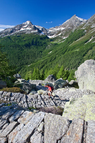 Hikers on the trail that climbs to the dam of Truzzo.  Valchiavenna. Vallespluga. Valtellina. Lombardy. Italy. Europe