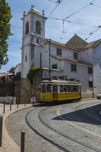 The yellow tram number 28 passes through the typical streets of the ancient Alfama district Lisbon Portugal Europe