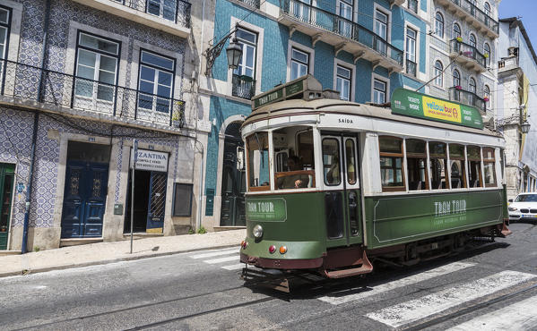 A typical tram takes tourists to discover the old city of Lisbon with its architecture and colorful houses Portugal Europe