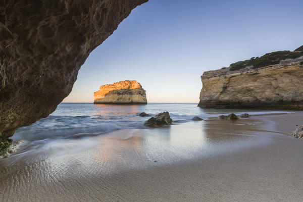 A sea cave frames the beach of Praia De Albandeira at dawn Carvoeiro Caramujeira Lagoa Municipality Algarve Portugal Europe