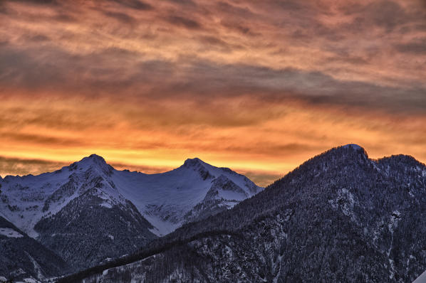 A winter sunset warms the atmosphere in Bitto Valley of Albaredo after a heavy snowfall. Rasura. Valgerola. Alps Orobie. Valtellina. Lombardy. Italy. Europe