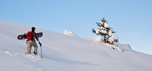 A hiker on snowshoes venture into the fresh snow as the moon appears on the horizon. Rasura. Valgerola. Alps Orobie. Valtellina. Lombardy. Italy. Europe