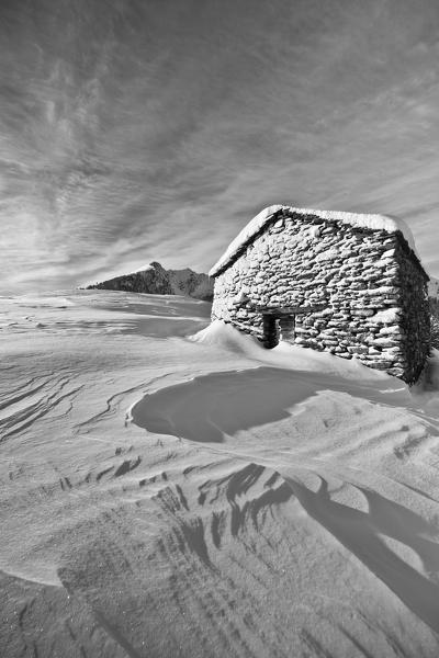 Black and white photograph depicting a cabin of Olano Alp whitewashed by a snow storm. Rasura. Valgerola. Alps Orobie. Valtellina. Lombardy. Italy. Europe