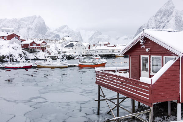 Icy sea and snowy peaks around the typical houses called rorbu and fishing boats Hamnøy Lofoten Islands Northern Norway Europe