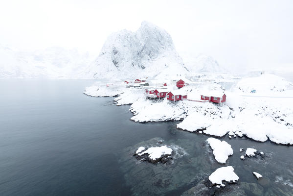 The snowy peaks and frozen sea frame the typical fisherman houses called Rorbu Hamnøy Lofoten Islands Northern Norway Europe