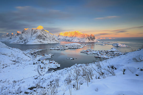 The pink colors of dawn frame the fishing villages and the frozen sea Reine Nordland Lofoten Islands Norway Europe