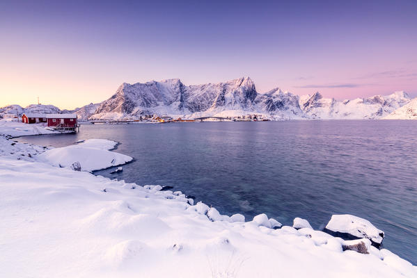 The colors of dawn frames the fishermen houses surrounded by frozen sea Reine Bay Nordland Lofoten Islands Norway Europe