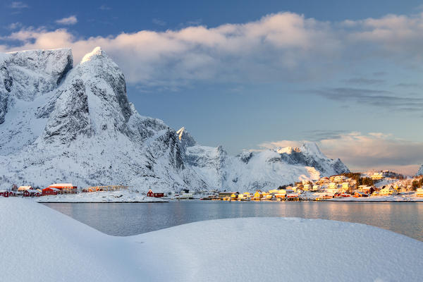 Sun on fishing village surrounded by snowy peaks and frozen sea Kvalvika Andøya Reine Nordland Lofoten Islands Norway Europe