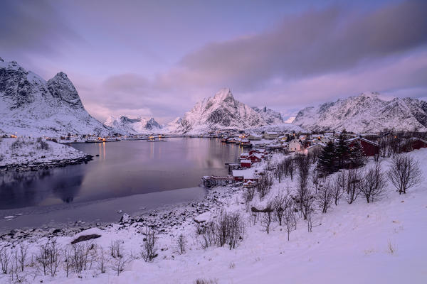 Colors of dawn on the fishermen houses surrounded by snowy peaks and frozen sea Reine Nordland Lofoten Islands Norway Europe