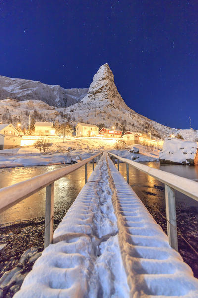 Starry night on the snowy peaks surrounded by the frozen sea Reinevagen Bay Nordland Lofoten Islands Norway Europe