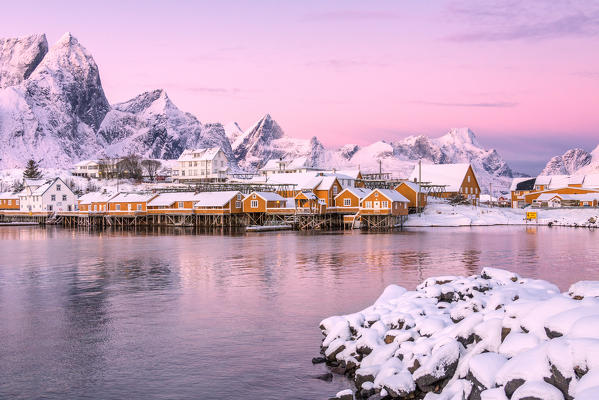 The colors of dawn frames the fishermen houses surrounded by snowy peaks Sakrisøy Reine Nordland Lofoten Islands Norway Europe