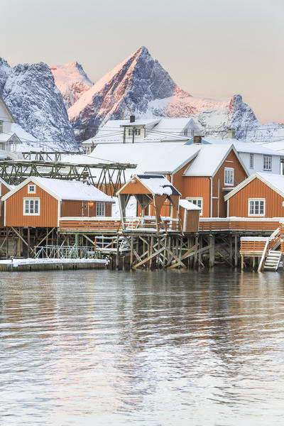 The colors of dawn frames the fishermen houses surrounded by snowy peaks Sakrisøy Reine Nordland Lofoten Islands Norway Europe