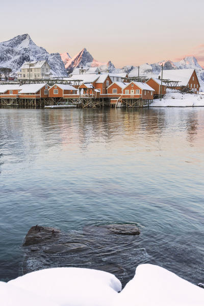 The colors of dawn frames the fishermen houses surrounded by snowy peaks Sakrisøy Reine Nordland Lofoten Islands Norway Europe