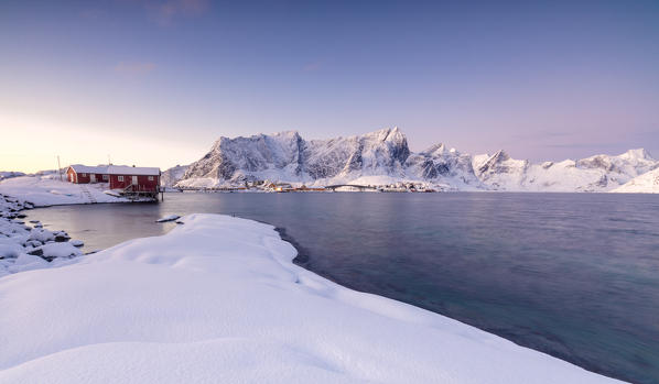 The colors of dawn frames the fishermen houses surrounded by frozen sea Sakrisøy Reine Nordland Lofoten Islands Norway Europe