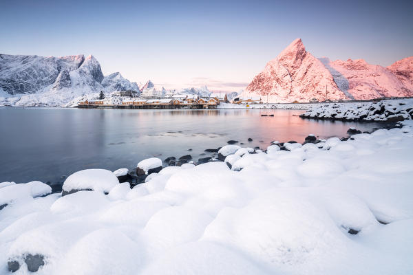 The colors of dawn frames the fishermen houses surrounded by snowy peaks Sakrisøy Reine Nordland Lofoten Islands Norway Europe