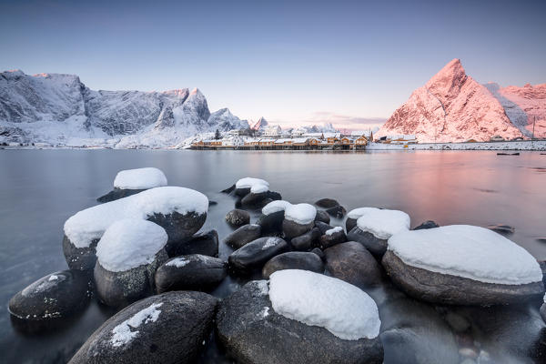 The colors of dawn frames the fishermen houses surrounded by frozen sea Sakrisøy Reine Nordland Lofoten Islands Norway Europe