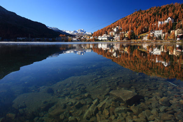 The houses of Saint Moritz reflected in their lake in autumn, high Engadine, Switzerland Europe