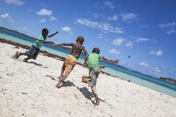 Children play on the beach surrounded by turquoise Caribbean Sea Green Island Antigua and Barbuda Leeward Island West Indies