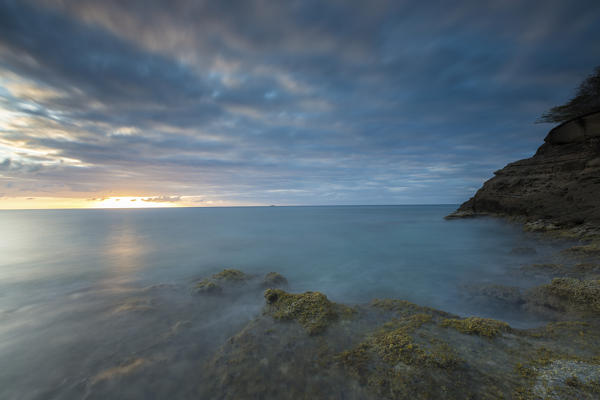 The lights of sunset are reflected in the blue sea Hawksbill Bay Caribbean Antigua and Barbuda Leeward Islands West Indies