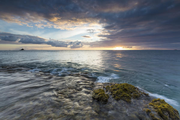 The lights of sunset are reflected in the blue sea Hawksbill Bay Caribbean Antigua and Barbuda Leeward Islands West Indies