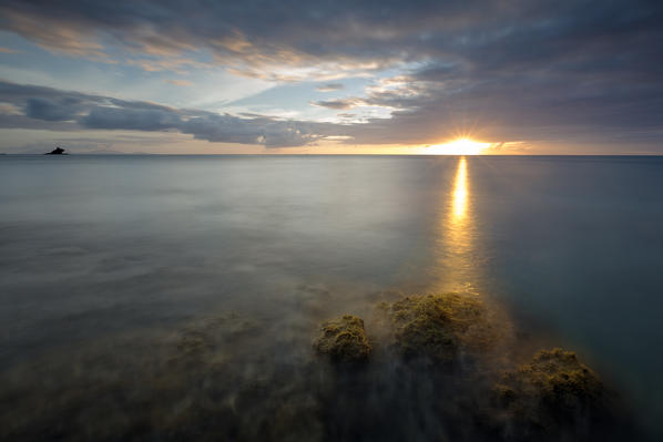 The lights of sunset are reflected in the blue sea Hawksbill Bay Caribbean Antigua and Barbuda Leeward Islands West Indies