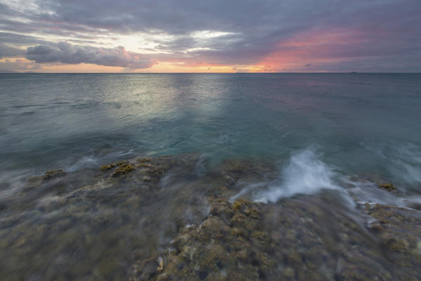 Waves crashing on cliffs under a fiery sky at sunset Hawksbill Bay Caribbean Antigua and Barbuda Leeward Islands West Indies