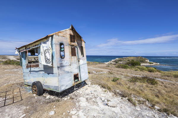 An abandoned roulotte frames the blue sea around the cliffs of Devil's Bridge Antigua and Barbuda Leeward Islands Antilles