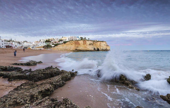 Ocean waves crashing on rocks and beach surrounding Carvoeiro village at sunset Lagoa Municipality Algarve Portugal Europe