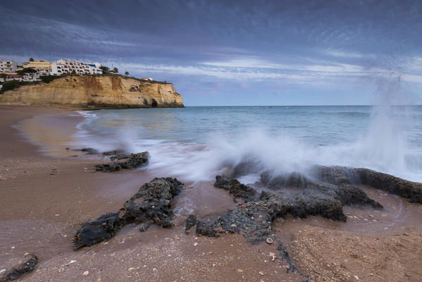 Ocean waves crashing on rocks and beach surrounding Carvoeiro village at sunset Lagoa Municipality Algarve Portugal Europe