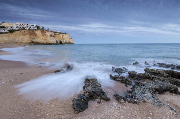 Ocean waves crashing on rocks and beach surrounding Carvoeiro village at sunset Lagoa Municipality Algarve Portugal Europe