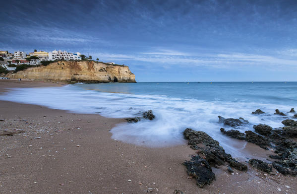 Ocean waves crashing on rocks and beach surrounding Carvoeiro village at sunset Lagoa Municipality Algarve Portugal Europe