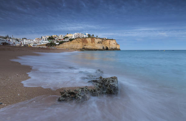 Ocean waves crashing on rocks and beach surrounding Carvoeiro village at sunset Lagoa Municipality Algarve Portugal Europe