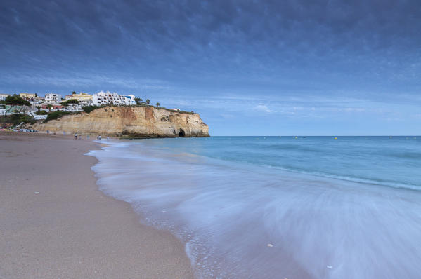 Ocean waves crashing on rocks and beach surrounding Carvoeiro village at sunset Lagoa Municipality Algarve Portugal Europe