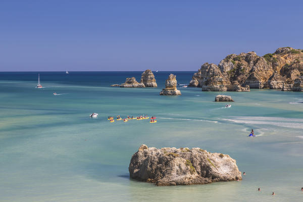 Canoes in the turquoise water of the Atlantic Ocean surrounding Praia Dona Ana beach Lagos Algarve Portugal Europe