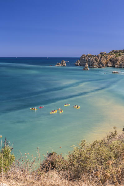 Canoes in the turquoise water of the Atlantic Ocean surrounding Praia Dona Ana beach Lagos Algarve Portugal Europe