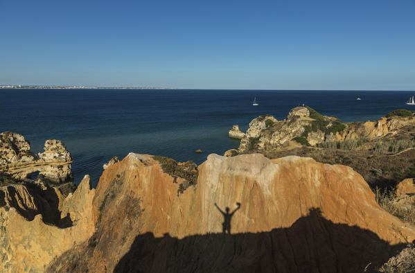 The shadow of the silhouette of a hiker reflected on the cliffs surrounding Praia Dona Ana beach Lagos Algarve Portugal Europe