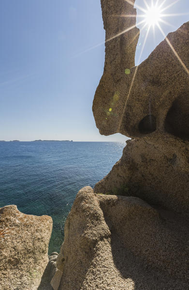 Sunbeams are reflected on the blue sea framed by rocks of the cliffs Punta Molentis Villasimius Cagliari Sardinia Italy Europe