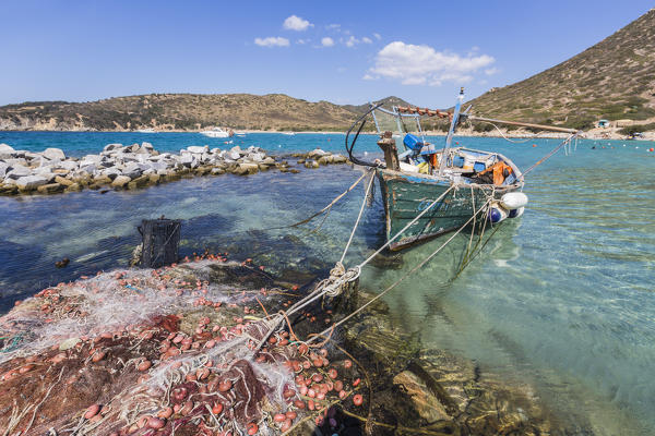 Fishing boat and nets in the turquoise sea surround the sandy beach Punta Molentis Villasimius Cagliari Sardinia Italy Europe