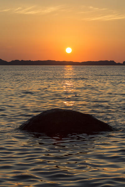 The newly risen sun on the blue sea tinged the sky of orange color Punta Molentis Villasimius Cagliari Sardinia Italy Europe