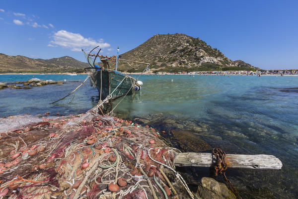 Fishing boat and nets in the turquoise sea surround the sandy beach Punta Molentis Villasimius Cagliari Sardinia Italy Europe