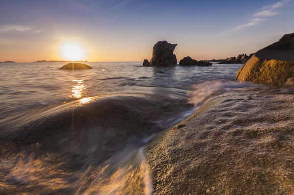 Waves crashing on cliffs under the fiery sky at sunrise Punta Molentis Villasimius Cagliari Sardinia Italy Europe