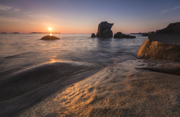 The golden lights of sunrise are reflected on the blue sea and cliffs Punta Molentis Villasimius Cagliari Sardinia Italy Europe